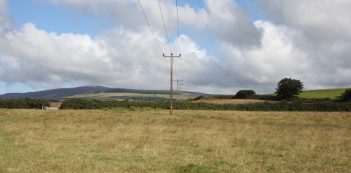 This image: a photo taken from the centre of the site, looking
					 		 northwest. The existing overhead cables are visible passing
							 through the site.
							 The map: The map shows satellite imagery behind the proposed site
							 boundary. Interactive map markers show more information about the
							 site environment when clicked on. These are also described in the
							 audio track below. Two further interactive markers show photos
							 looking towards the site from the A7 and the A5. From these
							 viewpoints, the site is barely visible, instead shielded by
							 neighbouring fields and field boundaries.